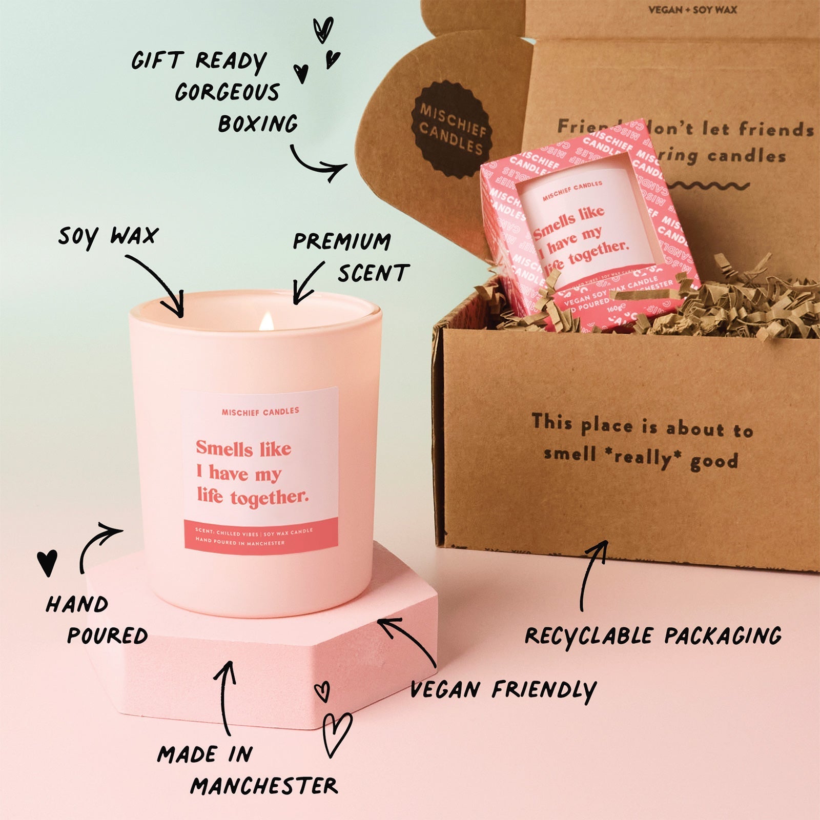 Pink candle with text highlighting features, next to a cardboard box with candles inside.