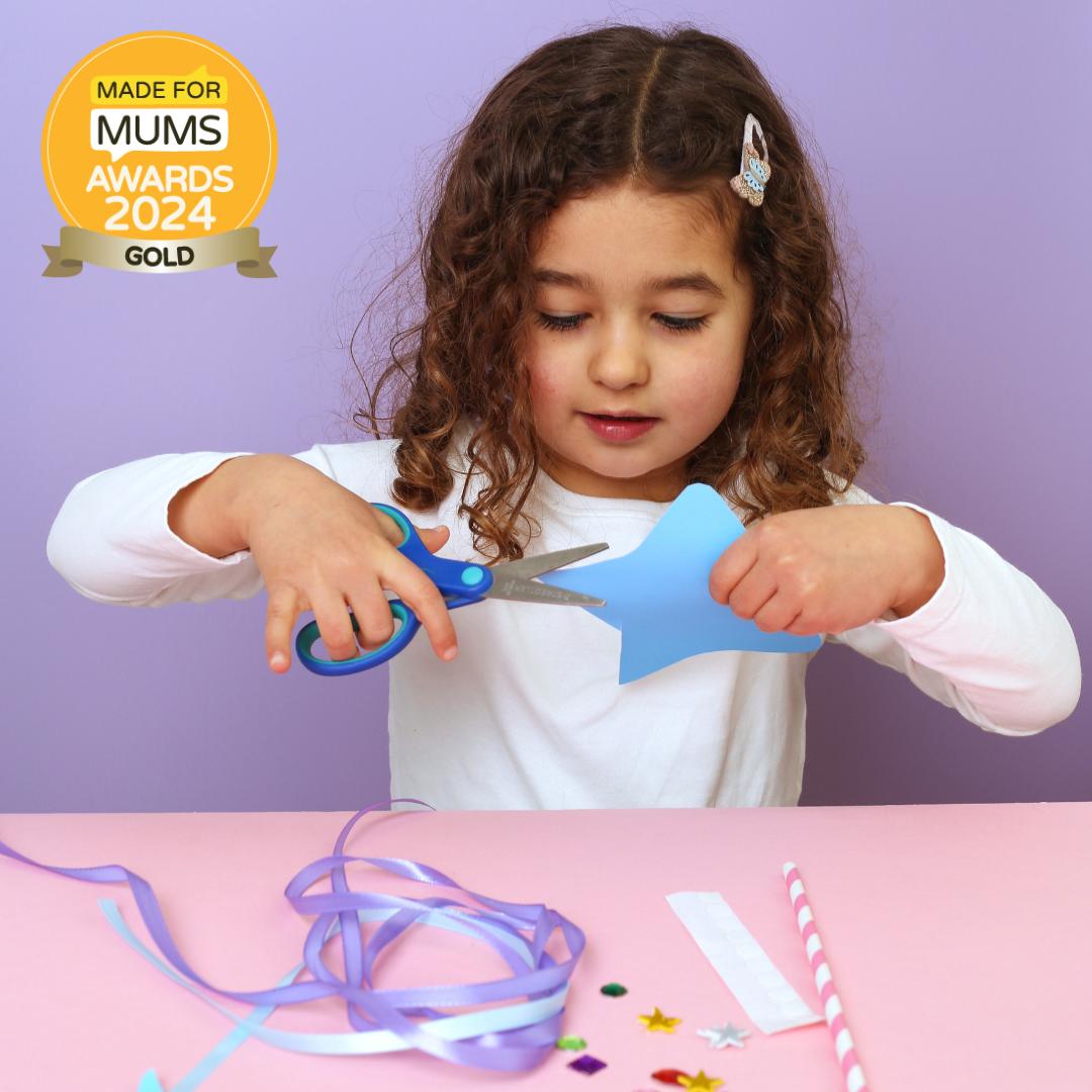 Child cutting blue paper with scissors on a pink table against a purple background, with 'Made for Mums Awards 2024 Gold' badge.
