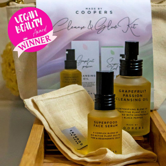 Coopers skincare products including cleansing oil, face serum, and a towel on a wooden tray with 'Vegan Beauty Award Winner' badge.
