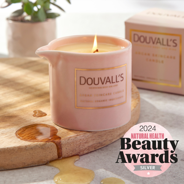 Pink Douvall's candle on a wooden board with a 2024 Natural Health Beauty Awards badge.