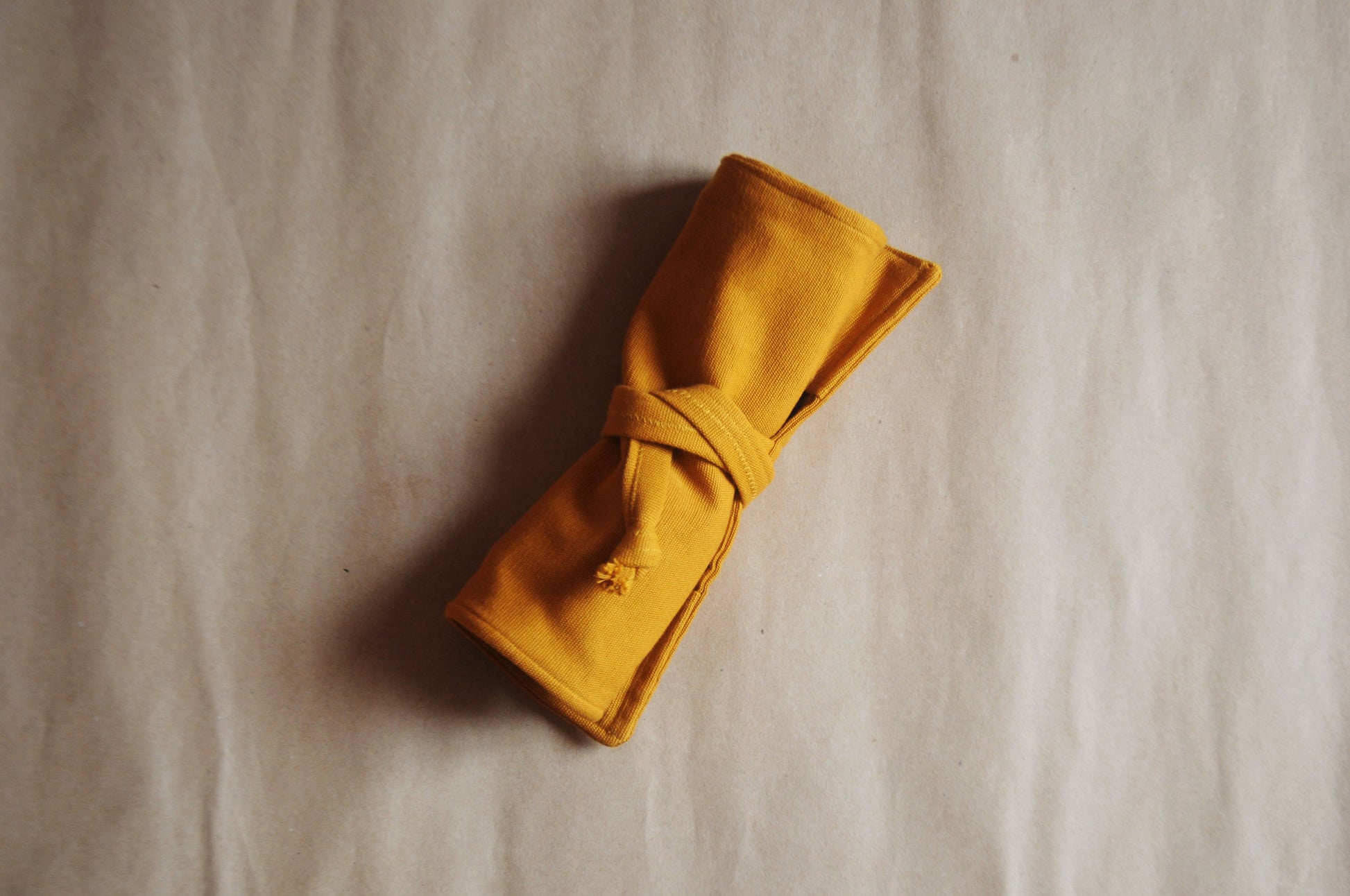 Rolled mustard yellow fabric on a textured beige surface