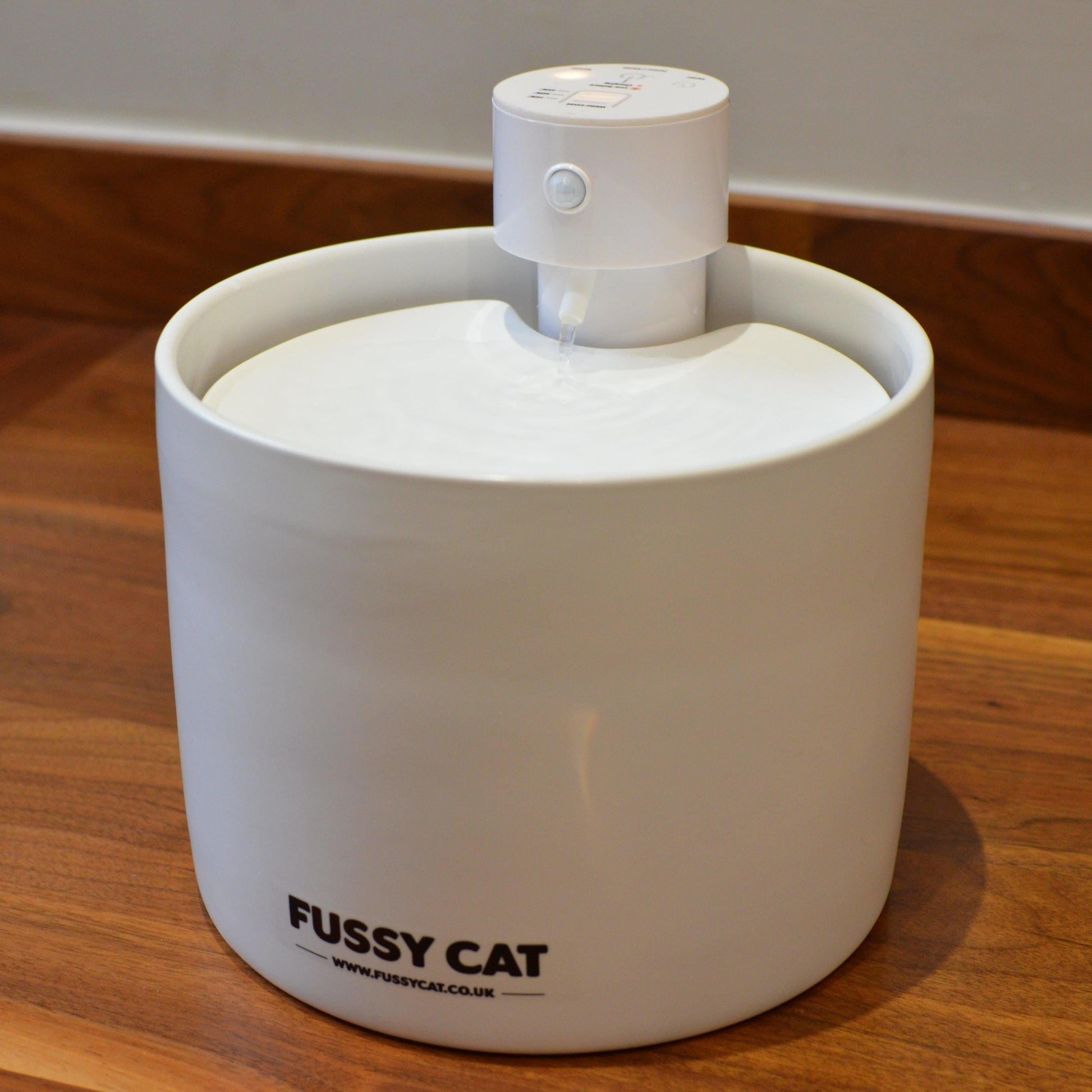 White pet water fountain with 'Fussy Cat' branding on a wooden surface