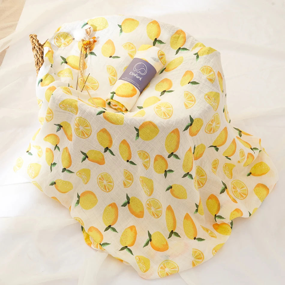 Fabric with lemon pattern and a rolled-up baby swaddle blanket on a white background