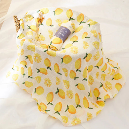 Fabric with lemon pattern and a rolled-up baby swaddle blanket on a white background