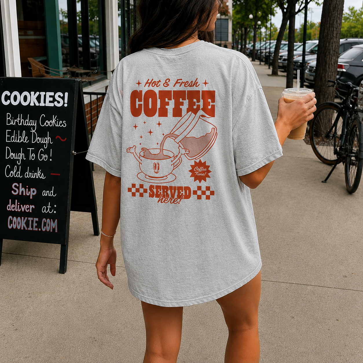 Person wearing a t-shirt with a coffee-themed design on a sidewalk.