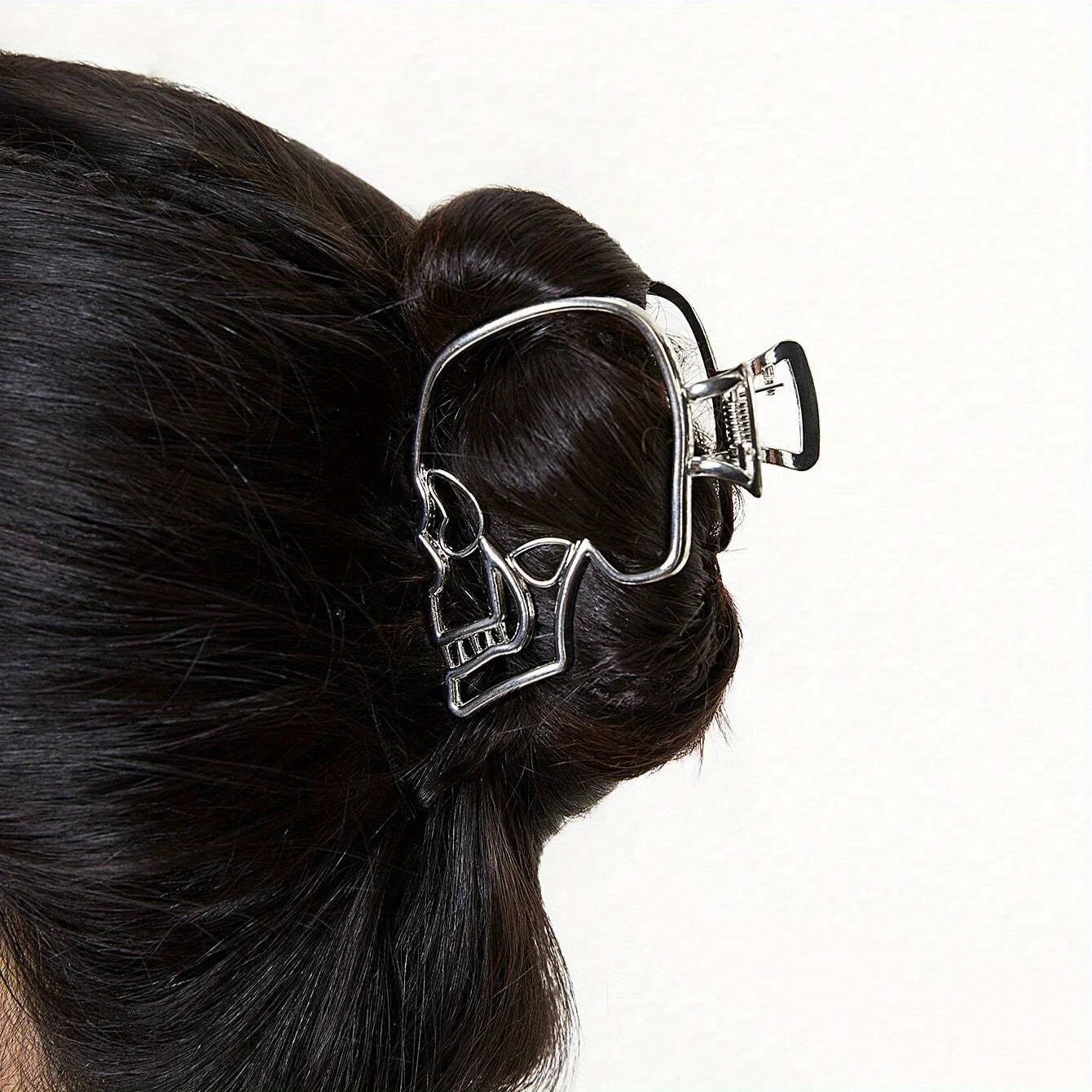 Skull-shaped hair clip on a person's hair against a white background