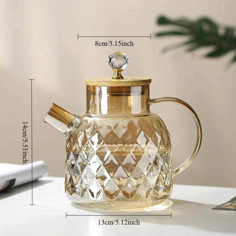 Glass teapot with gold accents and measurements on a neutral background