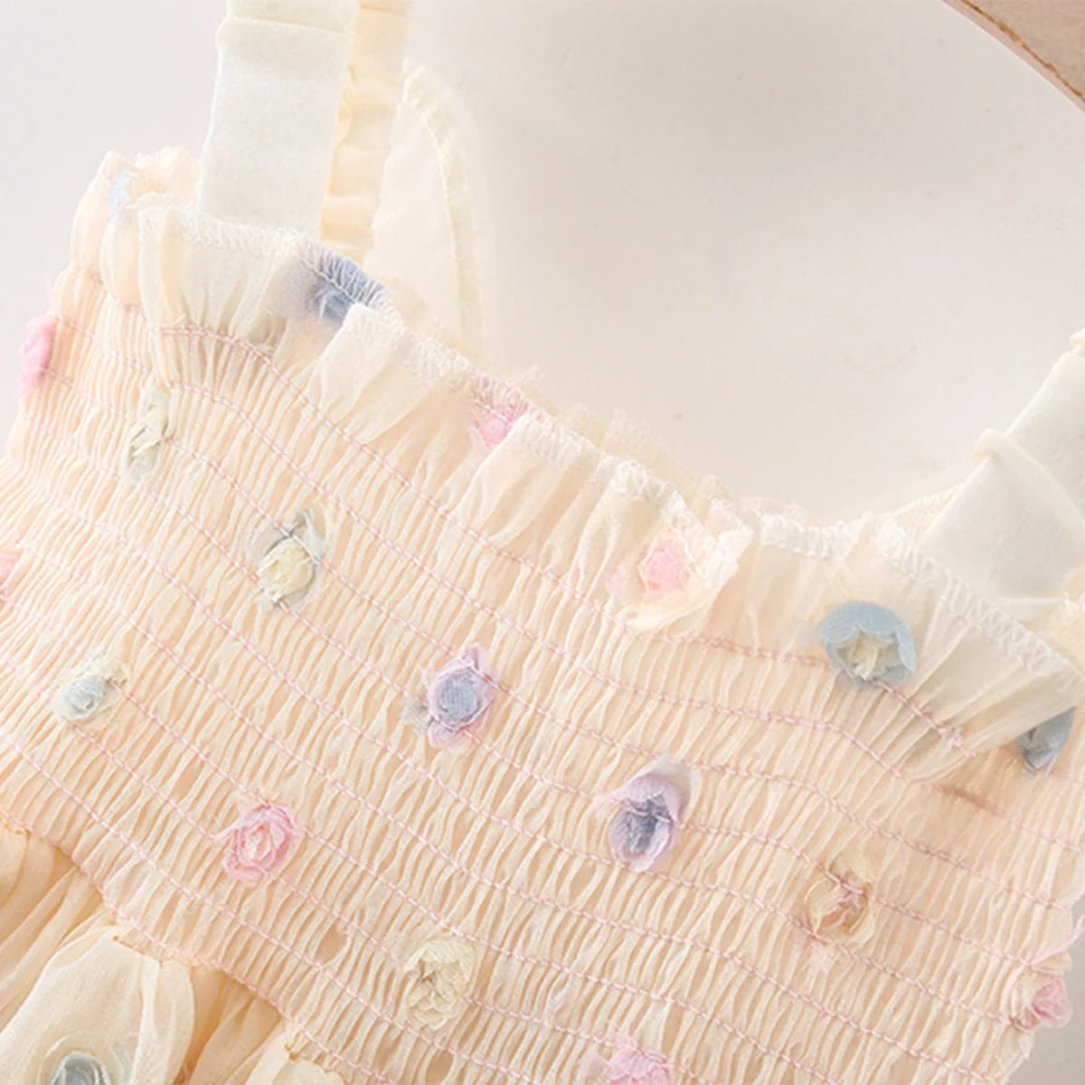 Close-up of a light pink dress with floral embellishments on a white background