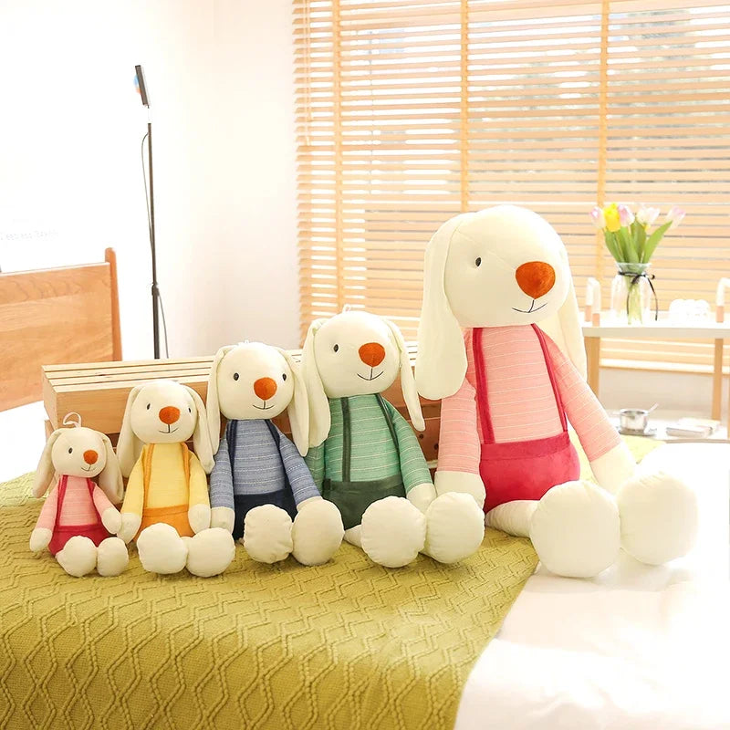 Set of colorful plush toys resembling bunnies on a bed.