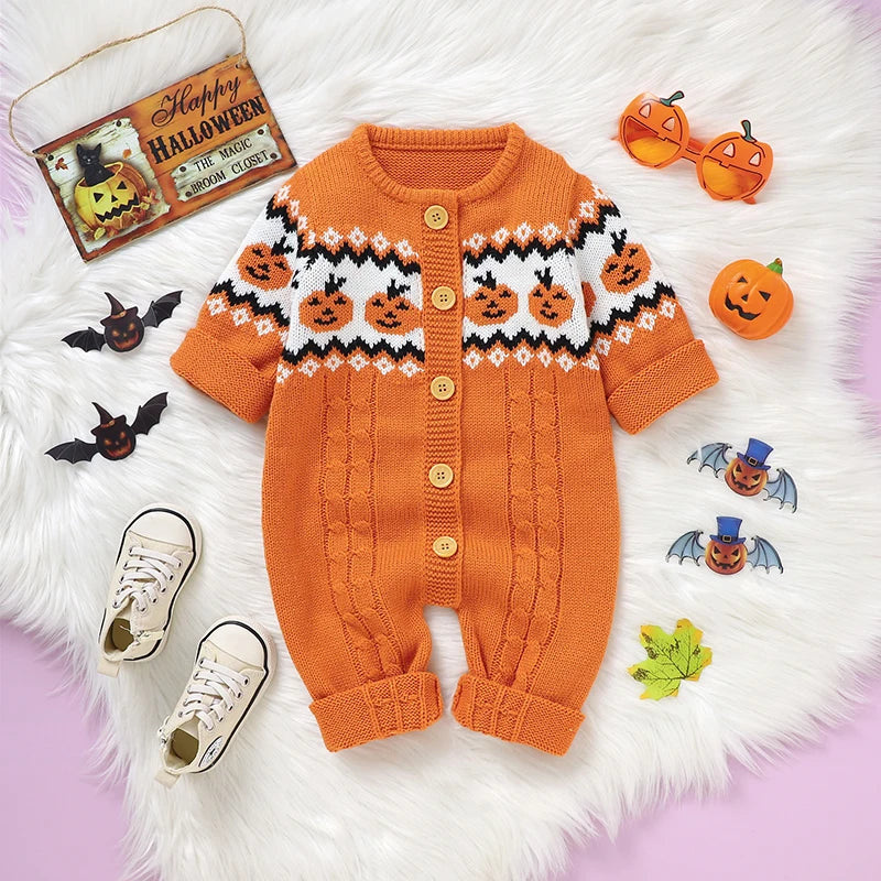 Orange baby romper with Halloween patterns on a white fur surface with decorative items.
