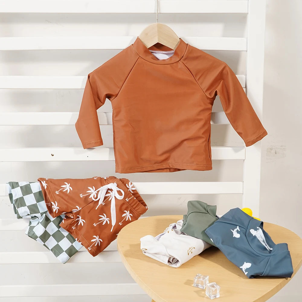 Children's swim set with a brown shirt and patterned pants on a wooden table against a white background.