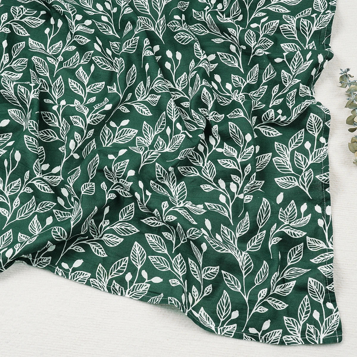 Green fabric with white leaf pattern on a white background