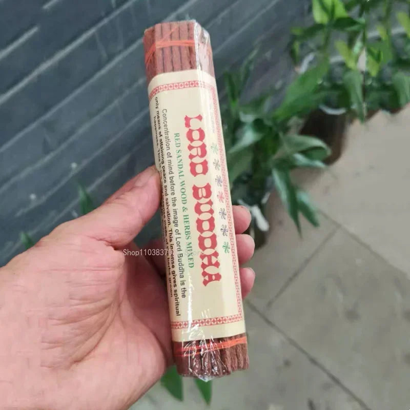 Hand holding a tube of Lord Buddha insence sticks with a blurred background