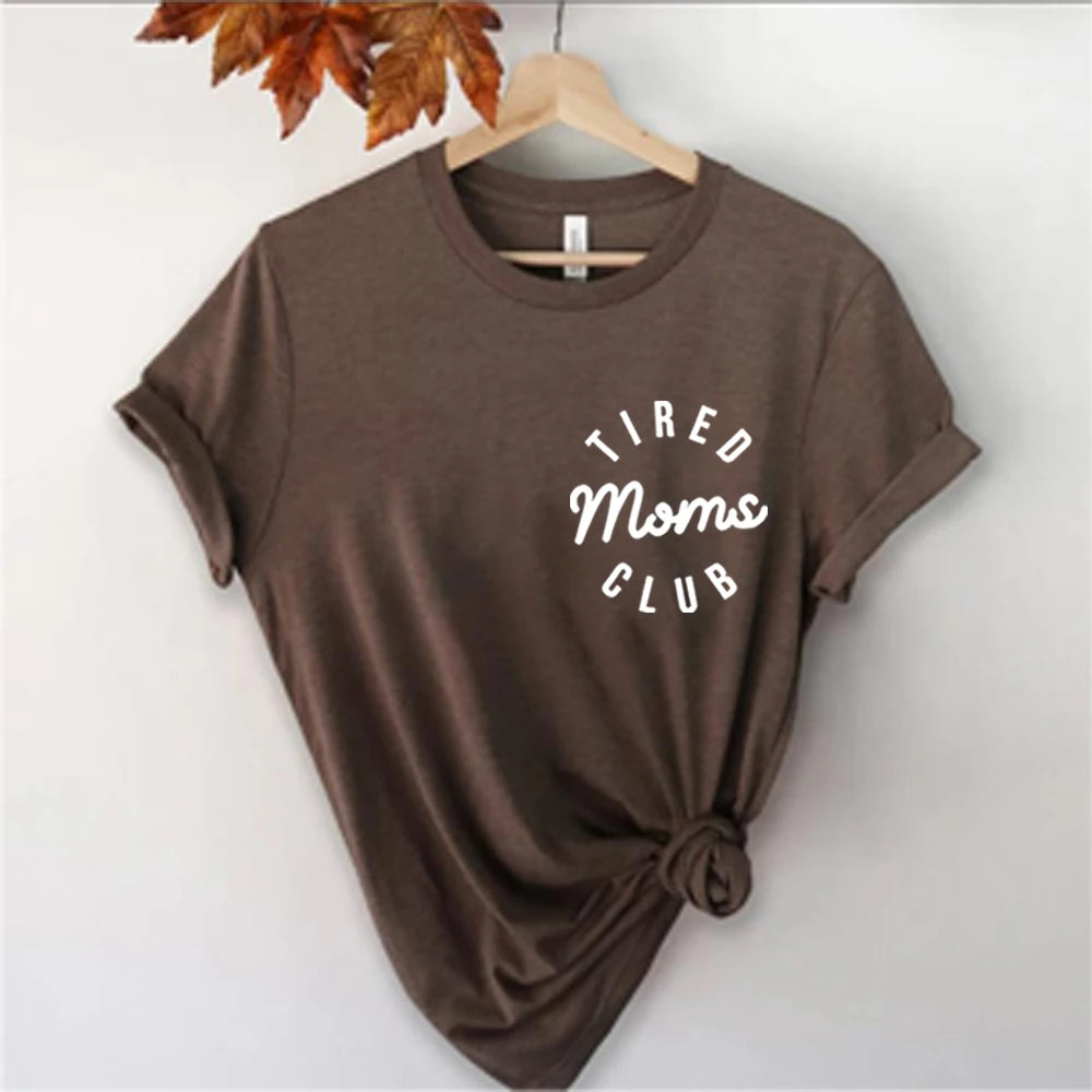 Brown t-shirt with 'Tired Moms Club' text on a hanger against a white background