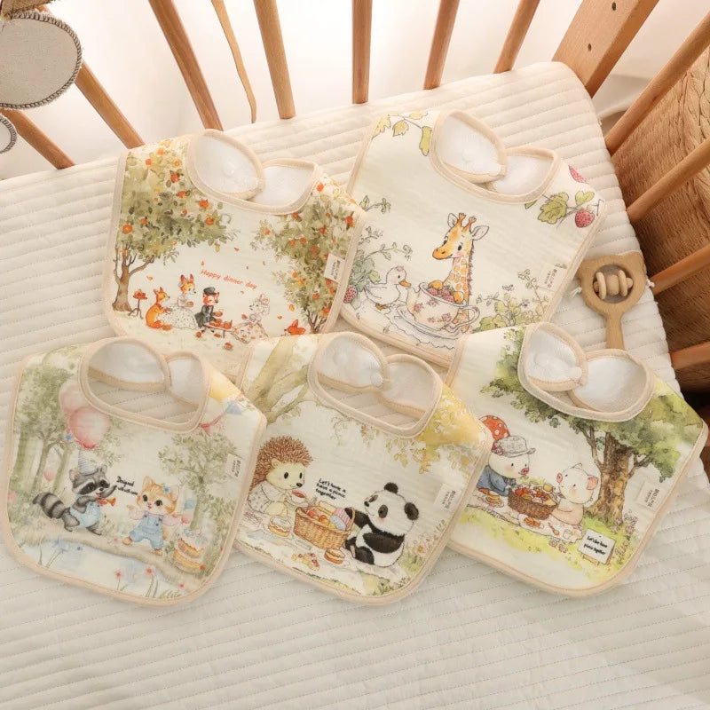 Set of baby bibs with animal illustrations on a crib