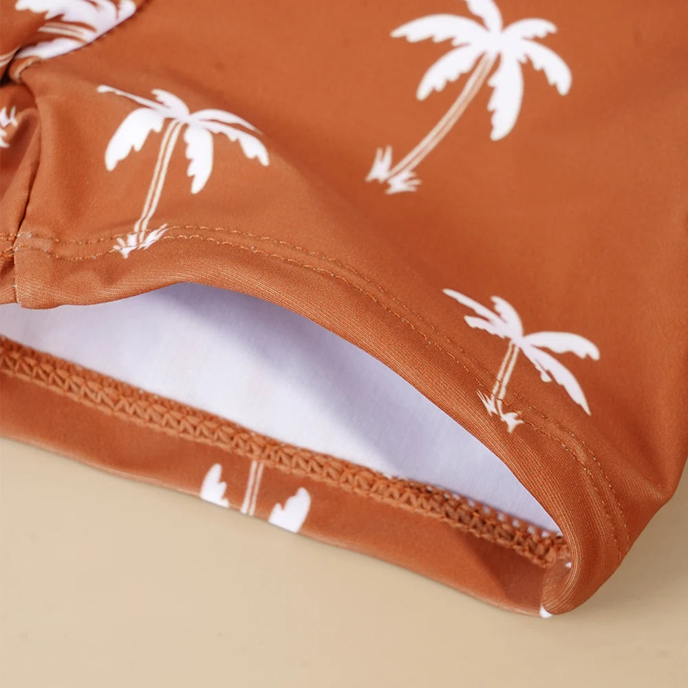 Close-up of a brown swimsuit with white palm tree pattern on a beige background
