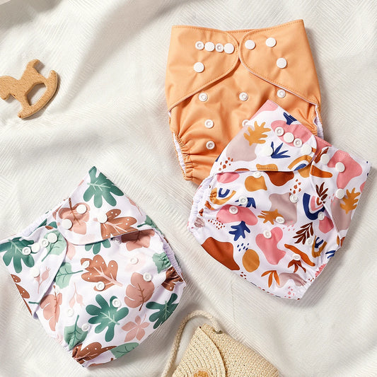 Three pairs of colorful baby diapers with floral patterns on a white surface.