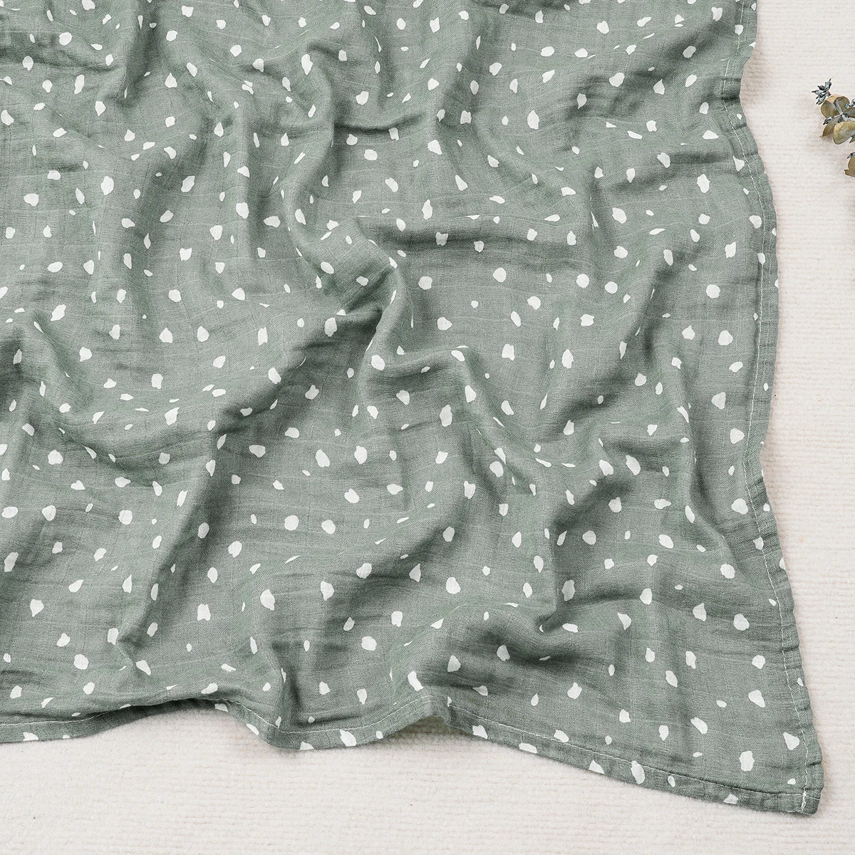 Green fabric with white heart pattern on a light gray background