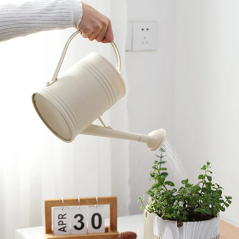 Person watering a plant with a beige watering can in a minimalistic setting.