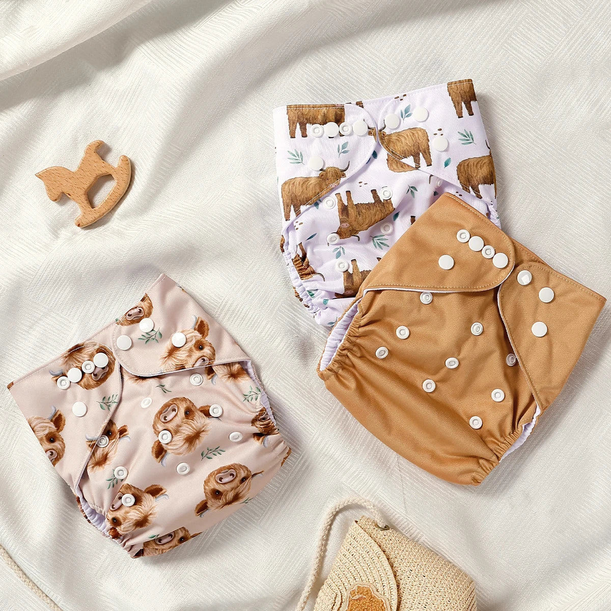 Three baby bloomers with animal prints on a soft white fabric background