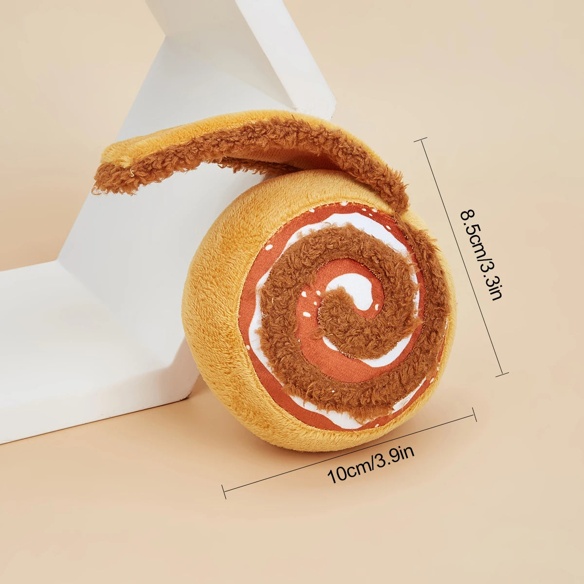 Toy resembling a cinnamon roll with dimensions indicated on a beige background