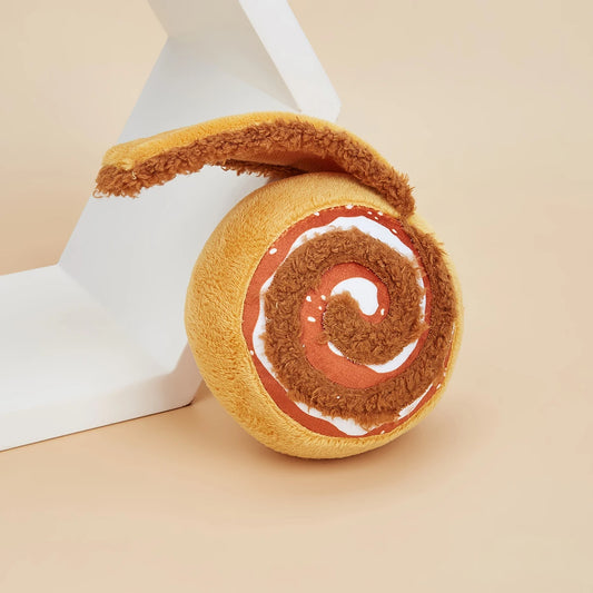 Dog toy resembling a cinnamon roll with white filling on a beige background