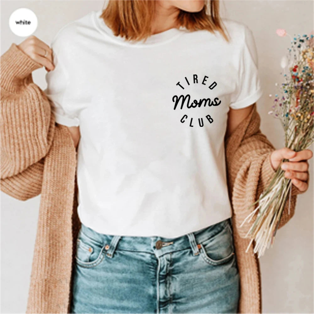 Person wearing a white t-shirt with 'Tired Moms Club' text, holding flowers, and wearing a beige cardigan.
