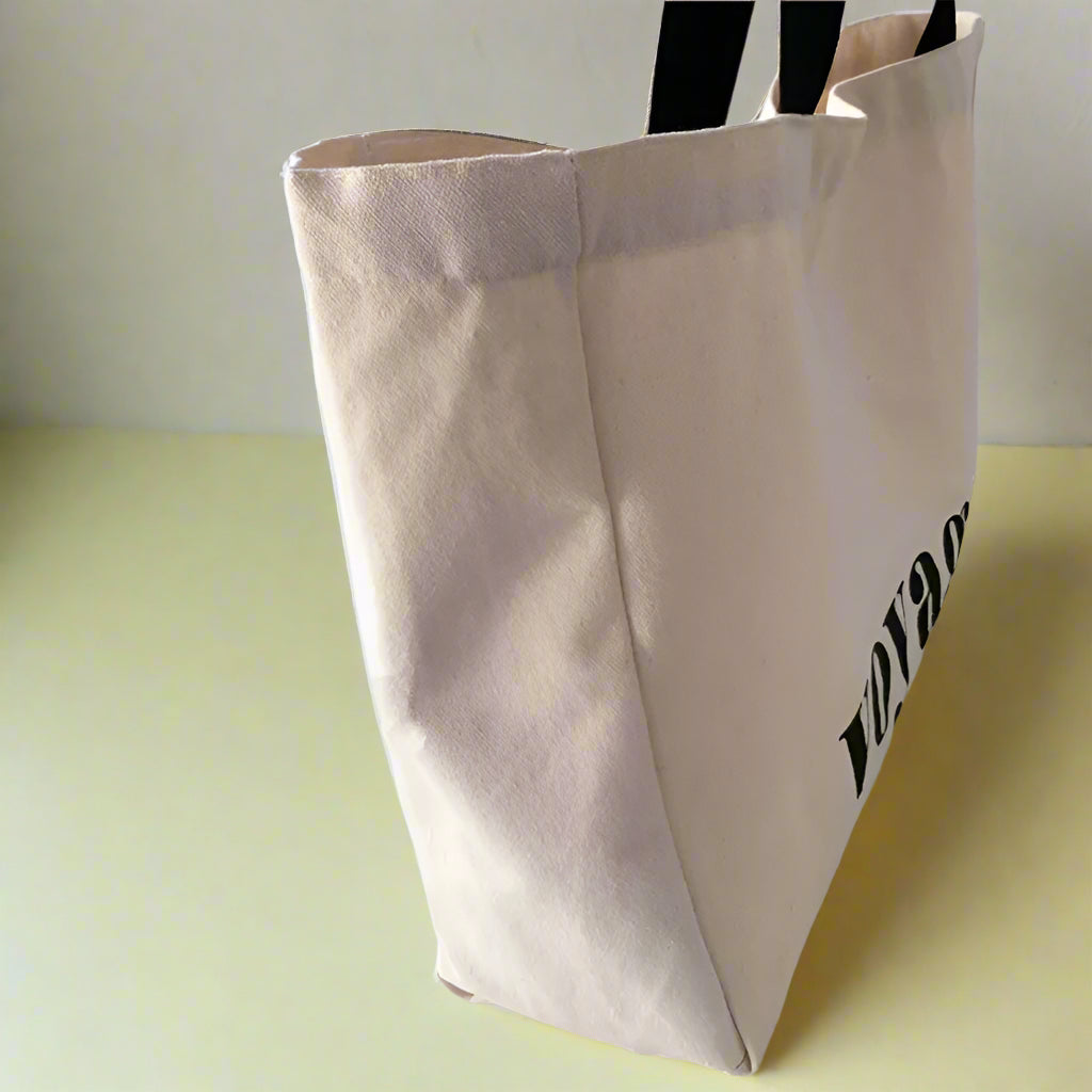 Beige tote bag with text on a white surface