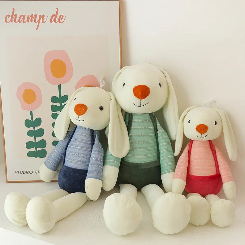 Three plush toy rabbits in front of a floral painting with 'champ de' branding.