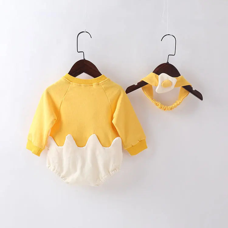 Yellow and white baby outfit on hangers against a white background