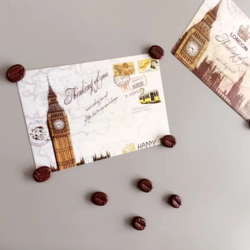 Card with Big Ben design and 'Thinking of you' message on a gray surface with coffee bean magnets