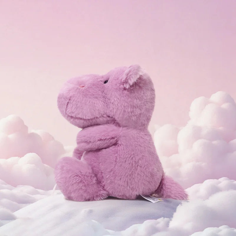 Purple plush toy hippo on fluffy white clouds with a soft pink background