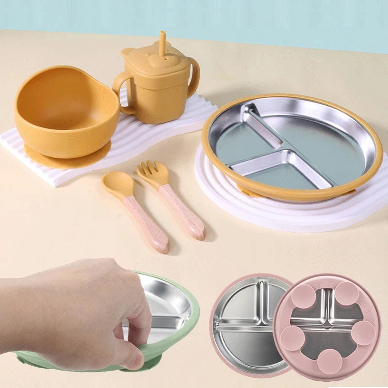 Children's dining set with bowl, cup, plate, and utensils on a beige surface.