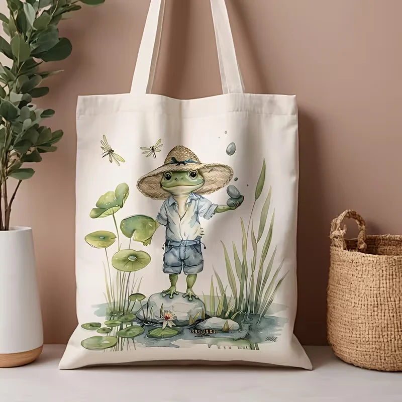 Tote bag with a frog illustration wearing a hat on a neutral background