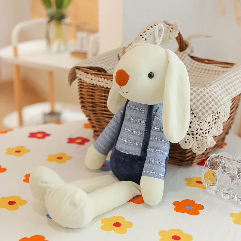 Stuffed bunny toy with a striped sweater on a floral blanket