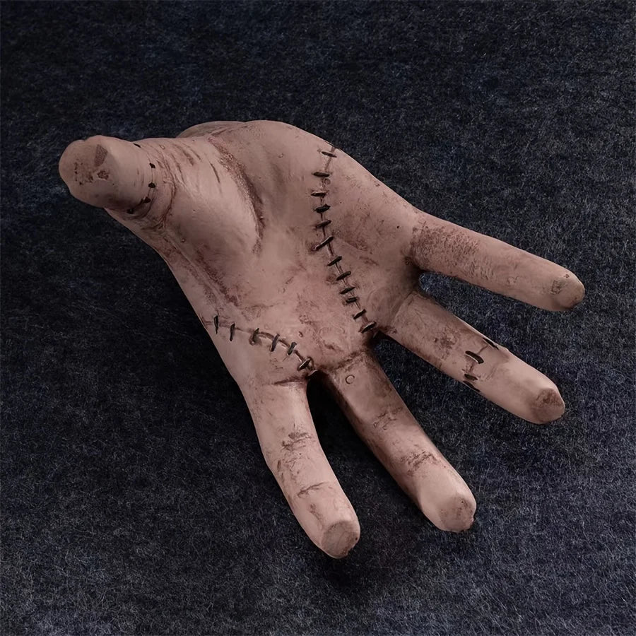 Textured hand sculpture with stitched details on a dark background