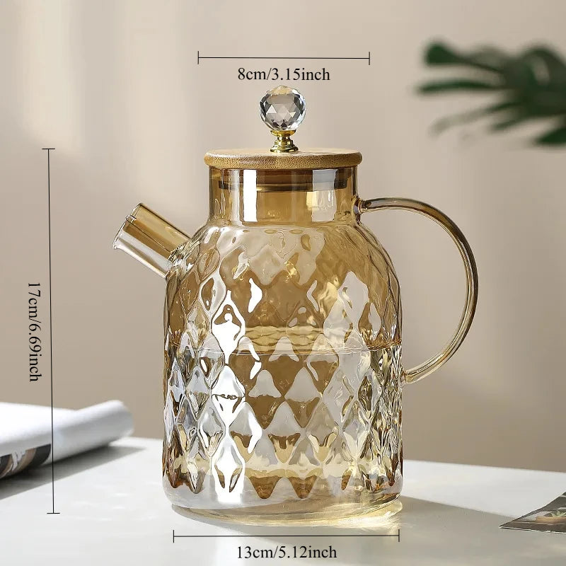 Glass teapot with gold accents and measurements on a neutral background