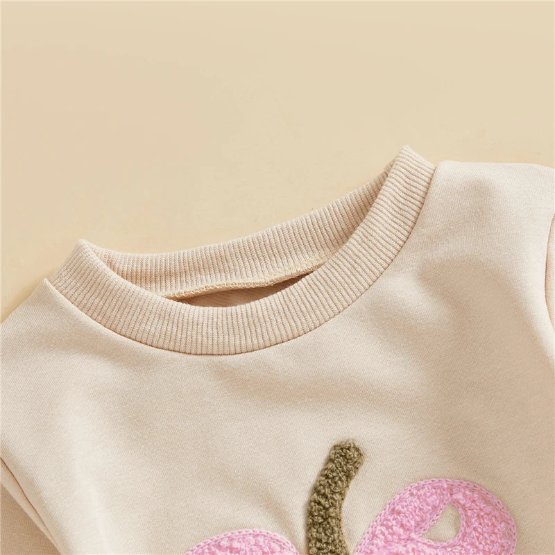 Close-up of a beige sweater with pink and green accents on a beige background