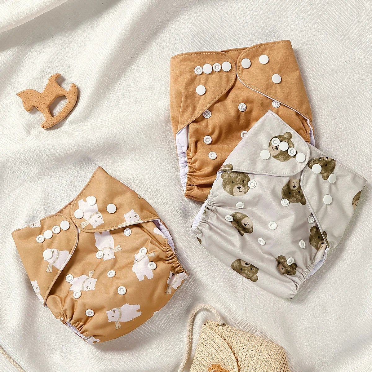 Two baby cloth diapers with bear pattern on a white fabric background