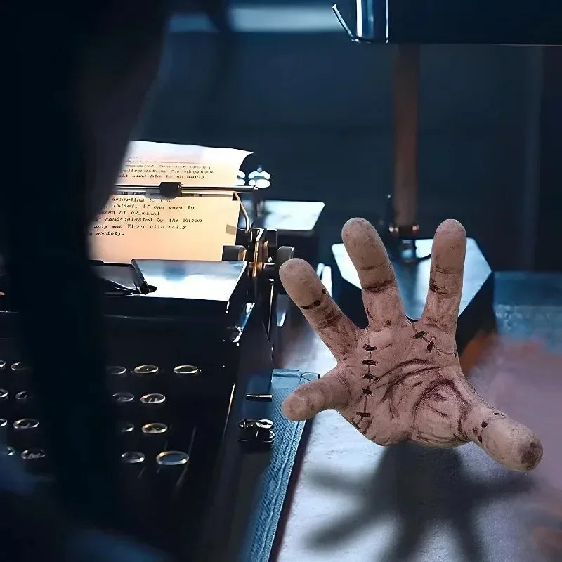 Hand with dark marks in front of a typewriter on a desk