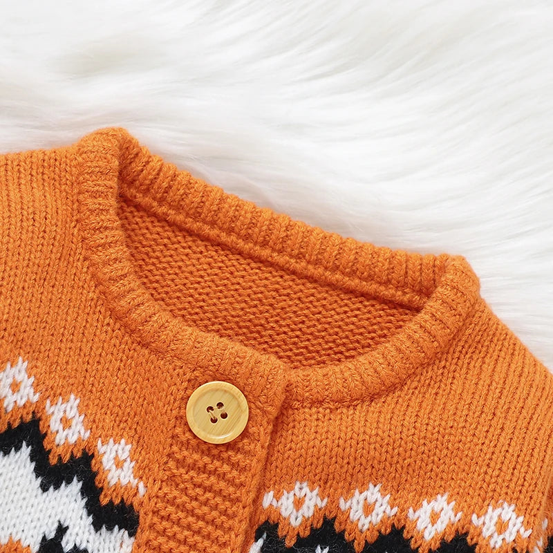 Close-up of an orange knitted cardigan with patterned details on a white background