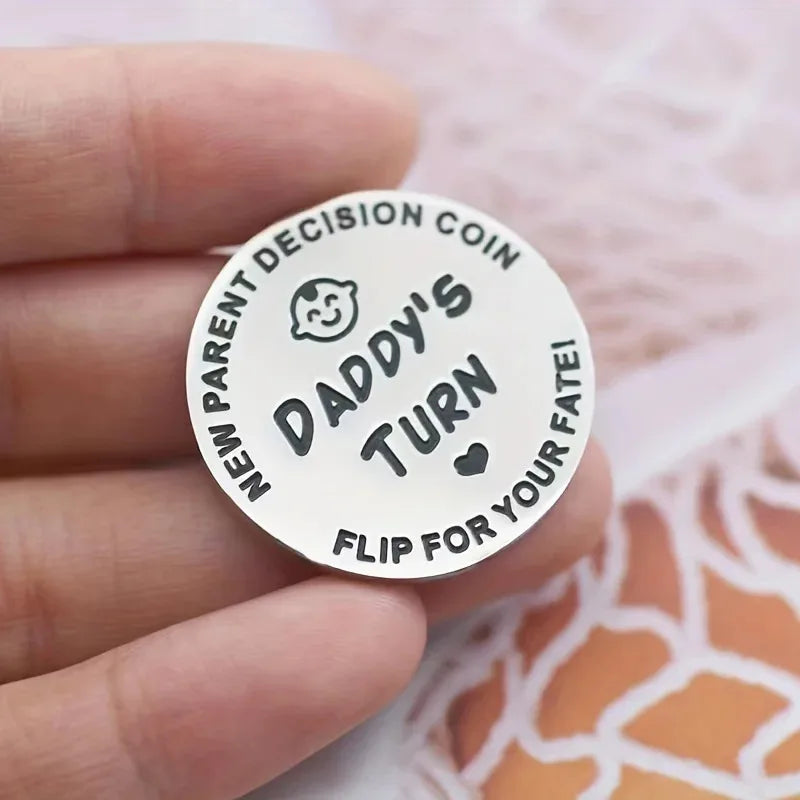 Round metal coin with text 'Daddy's Turn' held in a hand