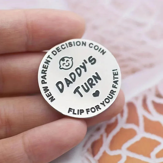 Round metal coin with text 'Daddy's Turn' held in a hand