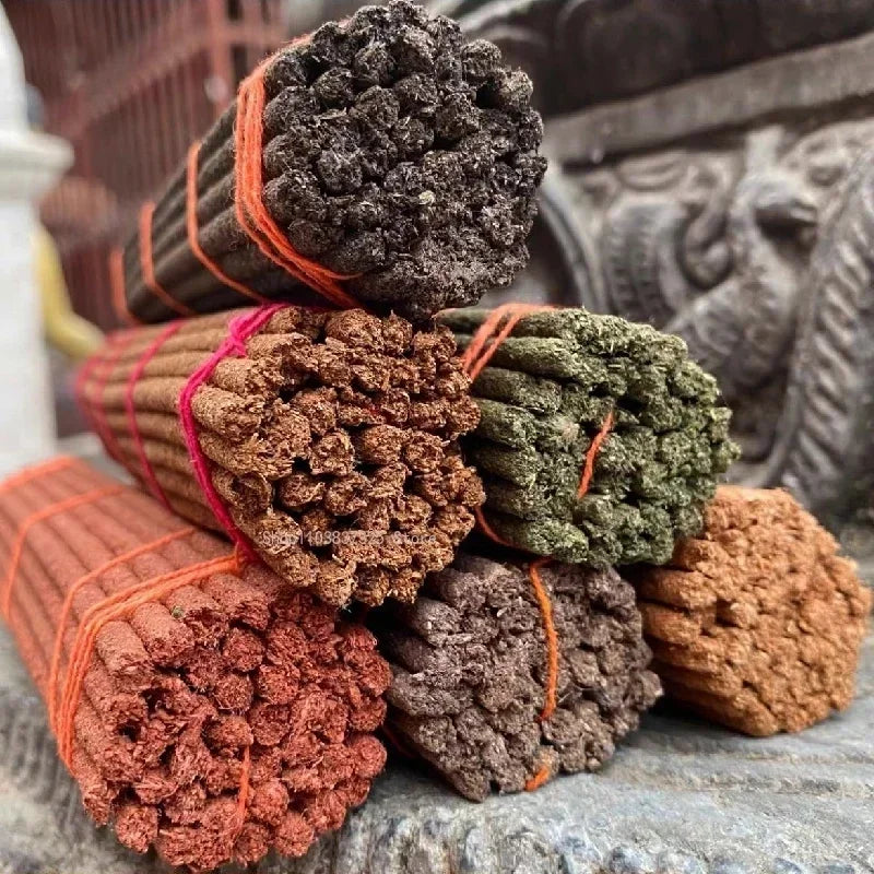 Stack of incense sticks tied with orange string on a stone surface