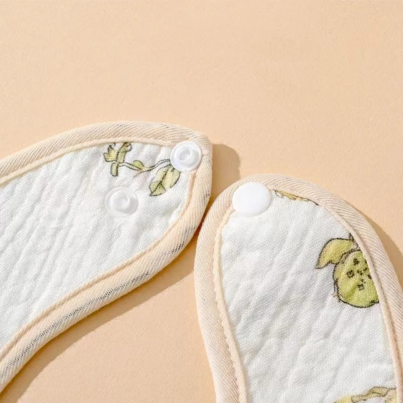 baby bib pop closure with floral embroidery on a beige background