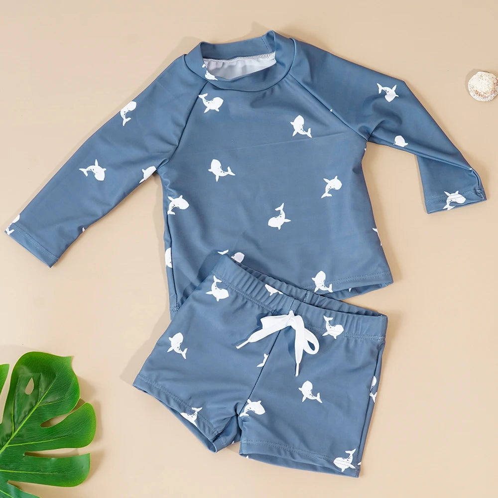 Children's blue rash guard set with white whale patterns on a beige background