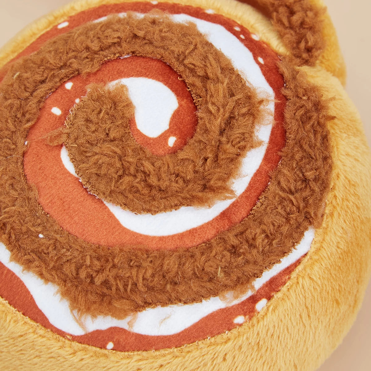 Plush toy resembling a cinnamon roll with brown, red, and white colors.