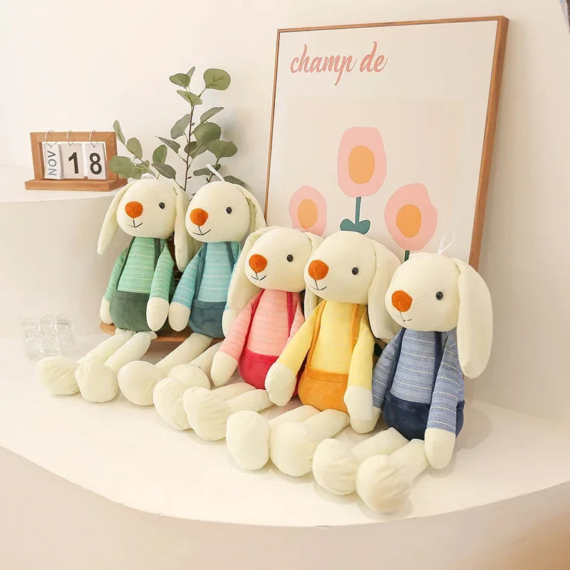 Set of plush toys resembling bunnies in various colors on a white surface with a decorative background.