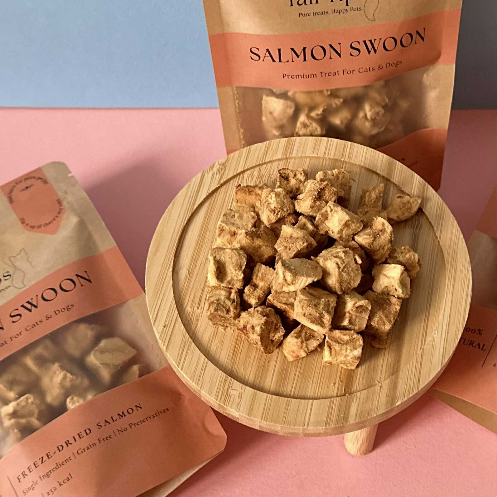 Salmon Swoon pet treats on a wooden plate with packaging in the background.