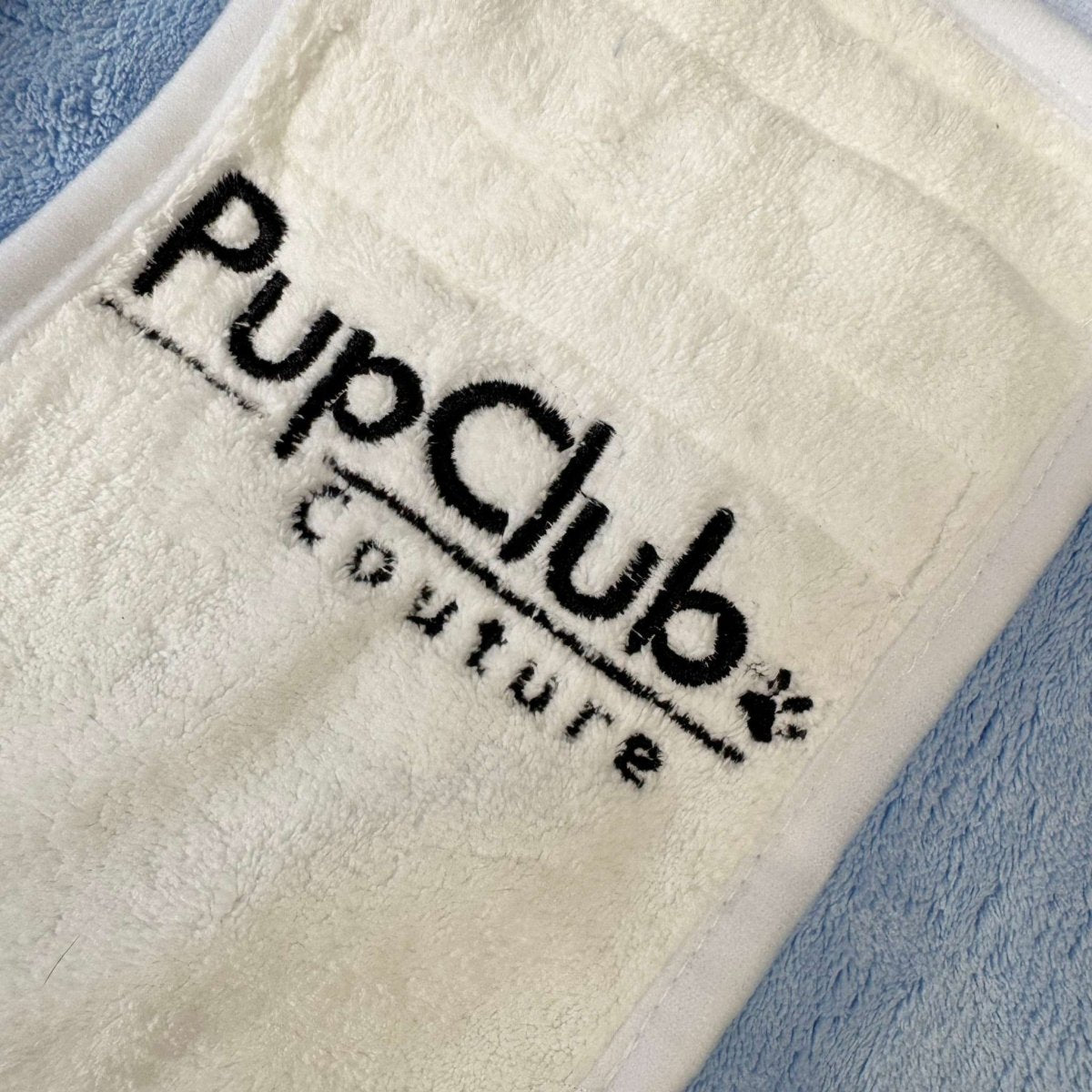 Beige towel with 'PupClub Couture' logo on a blue background